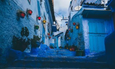 Colorful pots line the blue-washed walls of a narrow alley in Chefchaouen, Morocco.