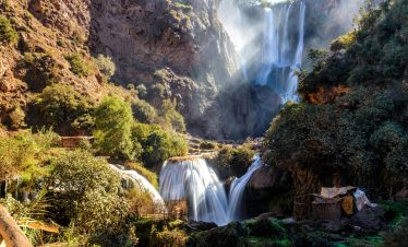 Stunning multi-tiered waterfalls cascading through mossy rocks in a lush forest setting under daylight.