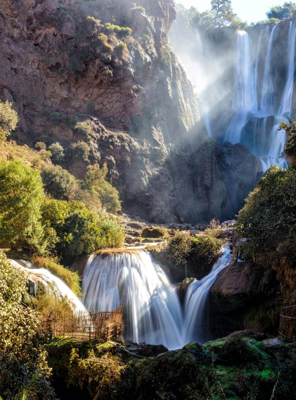 Stunning multi-tiered waterfalls cascading through mossy rocks in a lush forest setting under daylight.