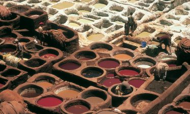 Overhead view of traditional tannery pits in Fez, Morocco with workers busy at work.