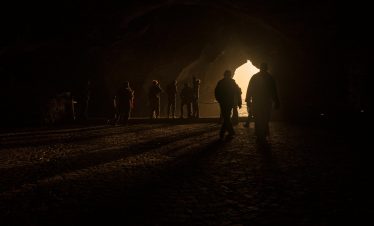 A group of silhouettes in the cave entrance backlit by sunlight in Tangier, Morocco.