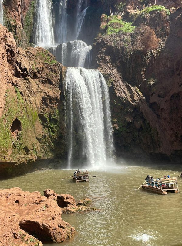 Capture of Ouzoud Waterfalls with tourists enjoying boat rides under the bright sun.