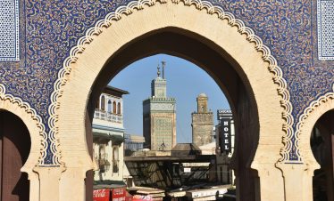 A view through Bab Bou Jeloud archway in Fès, revealing the city's historic architecture and skyline.
