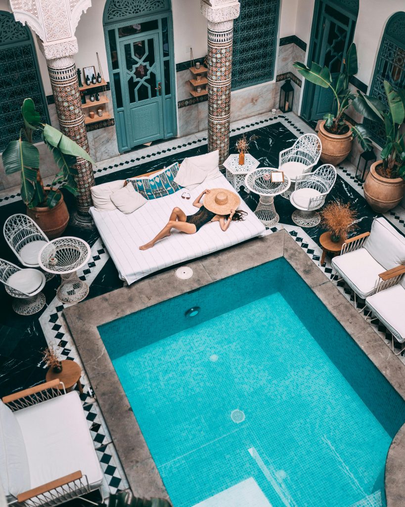 Elegant indoor pool with a woman lounging, set within a Moroccan riad in Marrakesh.